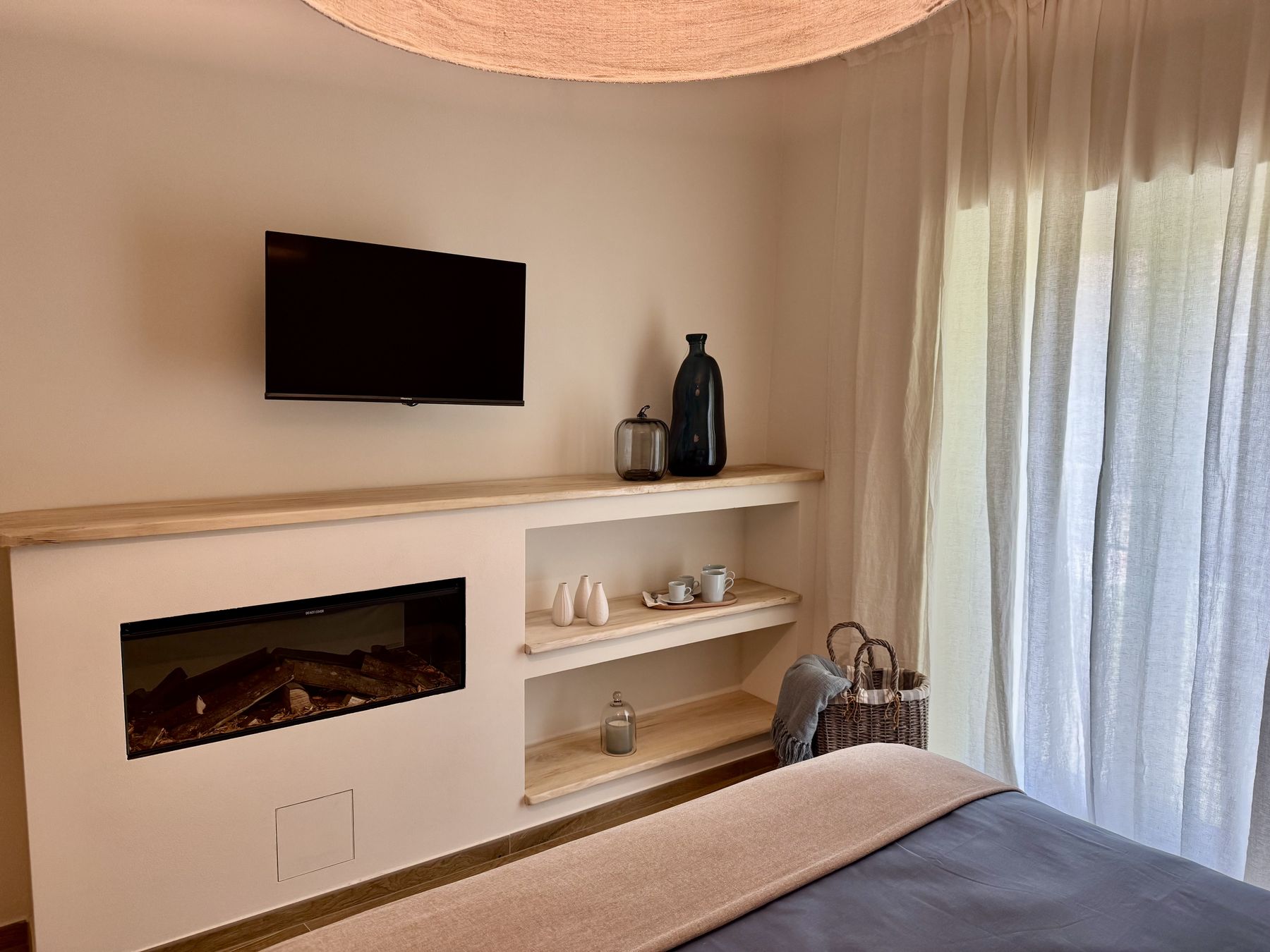 Il camino elettrico incassato fra le mensole in legno e la smart TV della Camera Aria